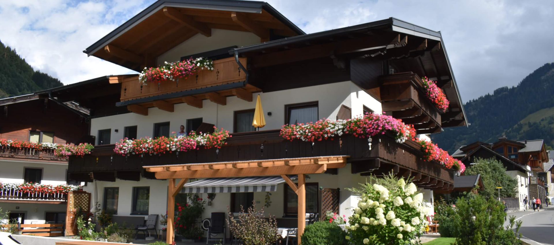 Pension Weinschreiber in Rauris mit blühenden Balkonen und Umgebung in den Alpen.